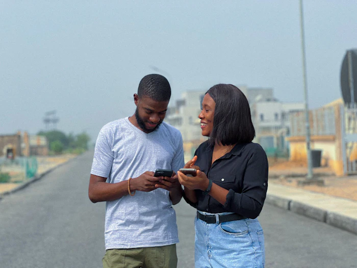 Two people looking at their phones in the street
