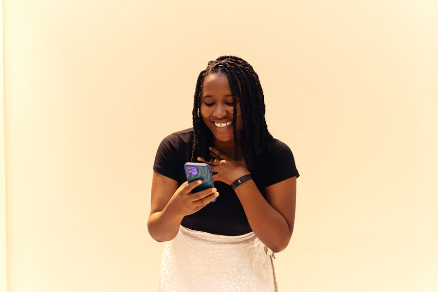 A young woman smiles while reading her phone